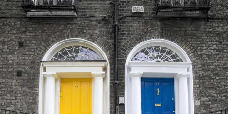 Eine blaue und eine gelbe Tür an einer Treppe sind die Eingänge eines Gebäudes.