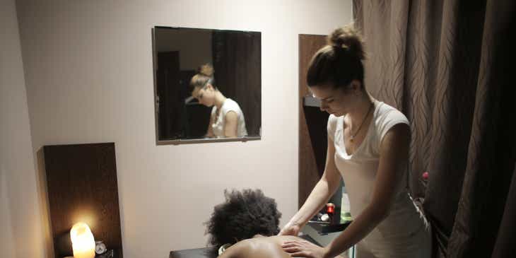 Masażystka wykonująca zabieg na plecach kobiety w gabinecie masażu.