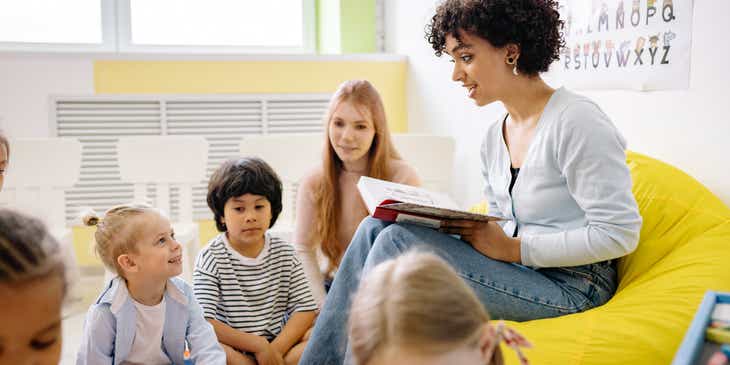 Bir anaokulunda çocuklara kitap okuyan bir öğretmen.