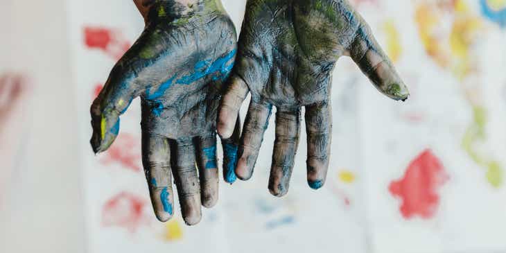Dua tangan yang dilumuri cat di kelas art therapy.