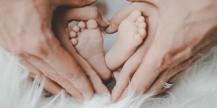 Frischgebackene Eltern halten sanft die Füße ihres Babys.