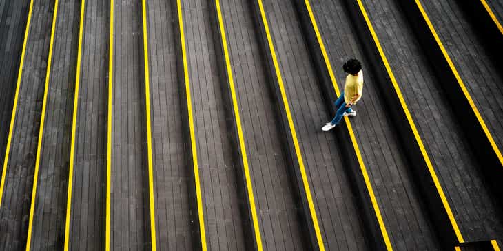 A person walking down black and yellow stairs.