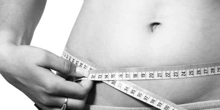 Une personne mesurant le ventre dans une clinique de remodelage corporel.