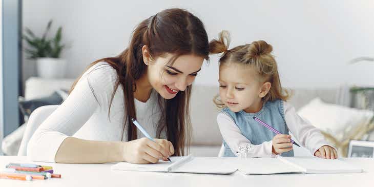 Kobieta pomagająca małej dziewczynce uczyć się pisać w ramach opieki nad dziećmi.
