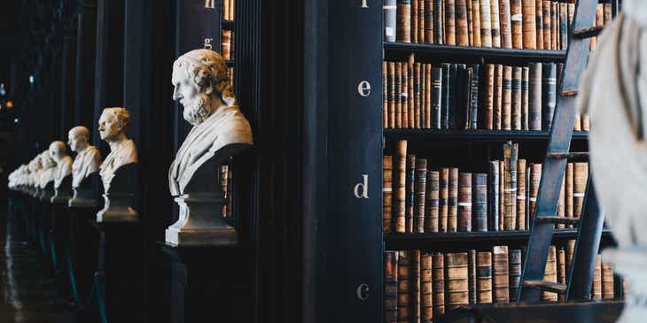 Une bibliothèque érudite avec des bustes de penseurs célèbres.