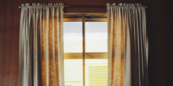 Gorden dan vitrase menutupi jendela besar di ruang tamu sebuah rumah.