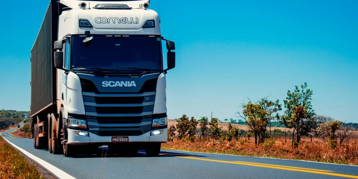 Un camion de transport blanc sur la route pendant une journée ensoleillée.