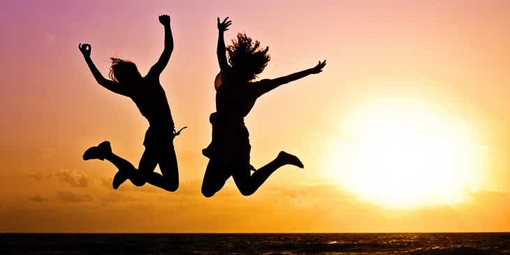Żywiołowe dziewczyny skaczące na tle zachodzącego słońca.