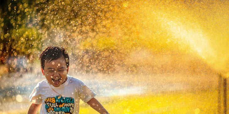 A happy child running through a sprinkler.
