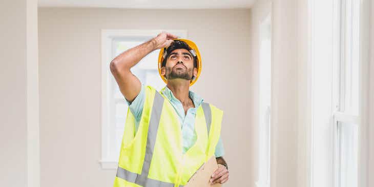 Ein Immobiliengutachter mit Sicherheitsausrüstung inspiziert eine neugebaute Immobilie.