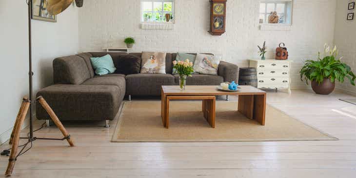 Wnętrze udekorowane brązową kanapa narożną, drewnianym stolikiem kawowym oraz innymi dekoracjami ze sklepu z wyposażeniem domu.