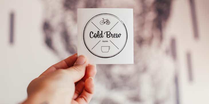 Eine Person hält einen Entwurf für ein Kaffeehaus-Logo in den Händen.