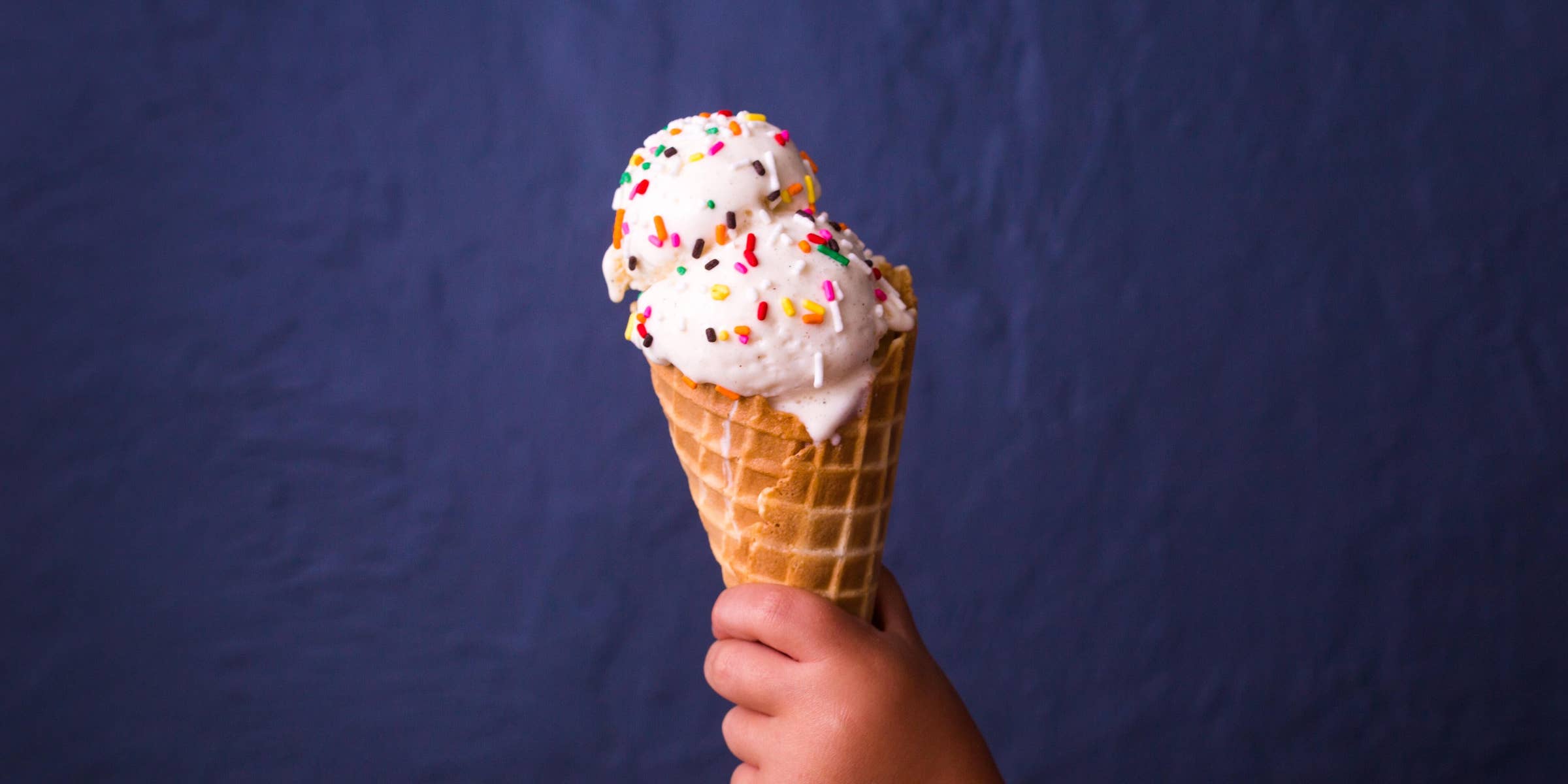 Delicious Pink Ice Cream with Sprinkles in a Waffle Cone on Blue