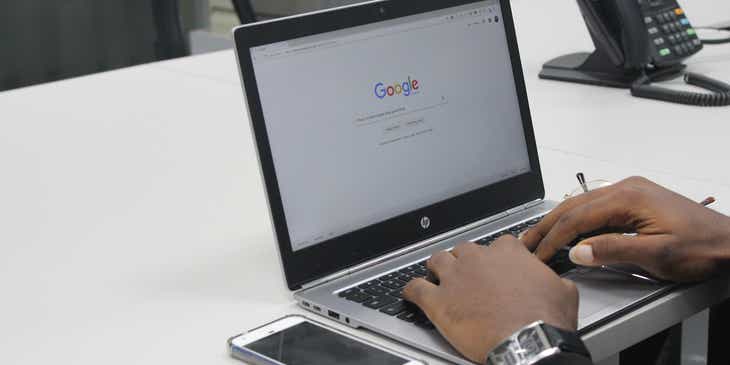 Ein Laptopnutzer sitzt an einem Schreibtisch und surft im Internet.