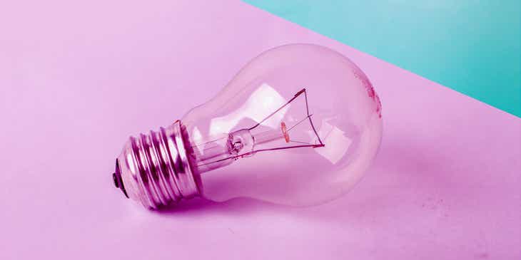 A light bulb on a pink and blue surface.