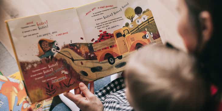 Seorang dewasa membacakan buku untuk seorang anak di bisnis penitipan anak.
