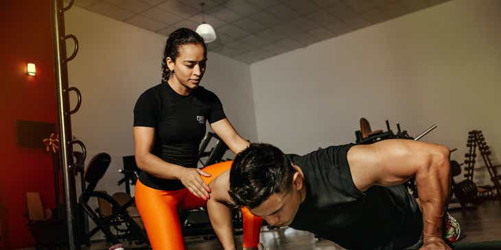 Seorang personal trainer membantu klien melakukan push-up.