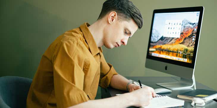 Ein Grafiker skizziert an seinem Schreibtisch das Redesign eines Logos.