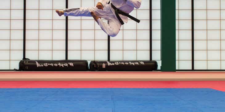 A man practicing martial arts by doing a flying kick.