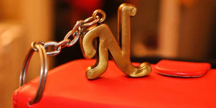 Gantungan kunci berbentuk huruf N yang terpasang pada dompet merah.
