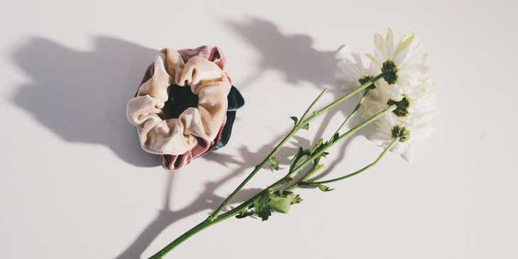 Scrunchies displayed on a white surface beside white flowers.