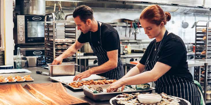 Dos personas ocupadas preparando platos para su negocio de servicio de catering, en un logo para empresas de servicios.
