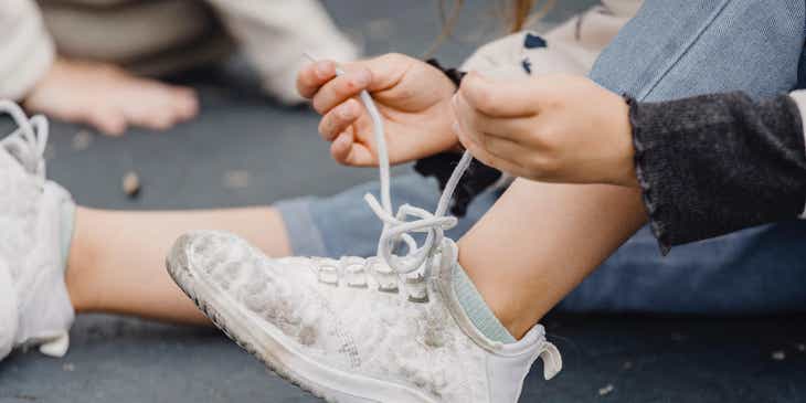 A person tying the laces of their sneaker.