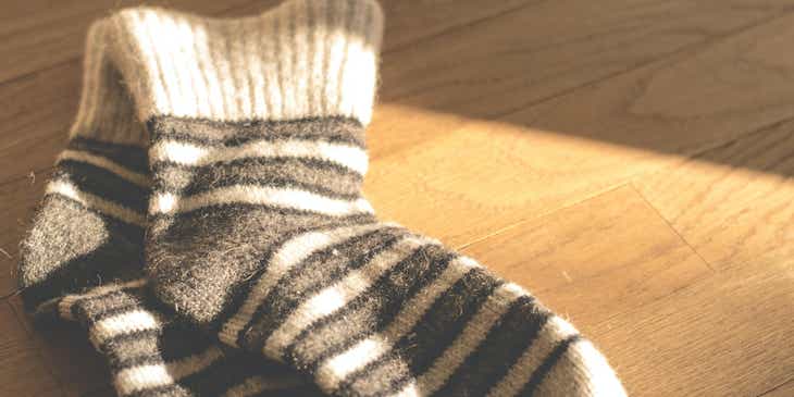Ein Paar flauschige Socken liegen auf einem sonnendurchfluteten Holzboden.