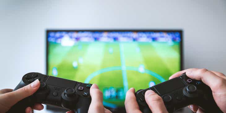 Zwei Personen halten Game-Controller und spielen auf einem großen Bildschirm ein spannendes Spiel.