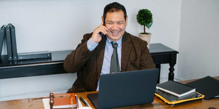 Ein Notar sitzt an seinem Schreibtisch und telefoniert mit seinem Handy.