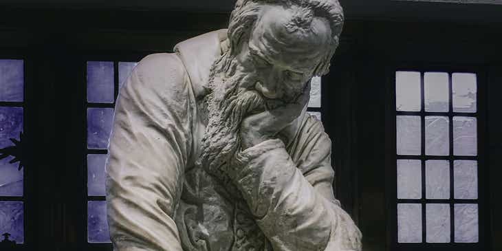 Una escultura de Galileo Galilei pensando de forma contemplativa en un logo con significado.