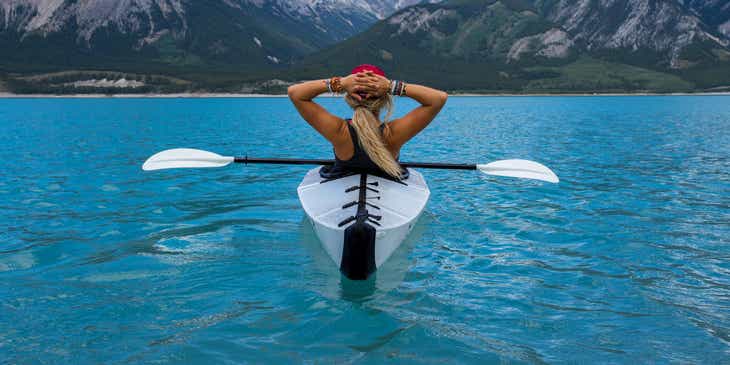 Una persona che fa kayak intenta ad ammirare il panorama durante uno stop nel suo viaggio avventuroso.