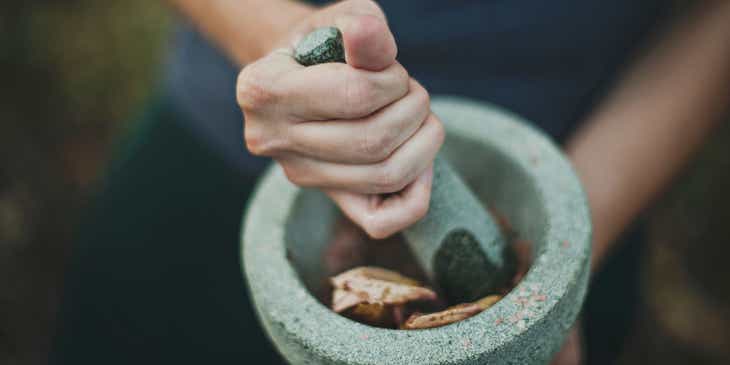 An apothecary grinding herbs with a mortar and pestle.