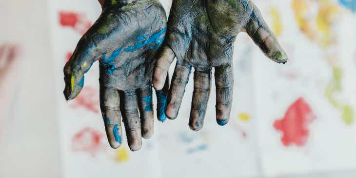 Mãos cobertas de tinta em uma aula de arteterapia.