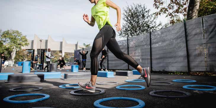 Eine sportliche Frau springt beim Fitness-Training von einem auf dem Boden platzierten Kreis zu dem nächsten.