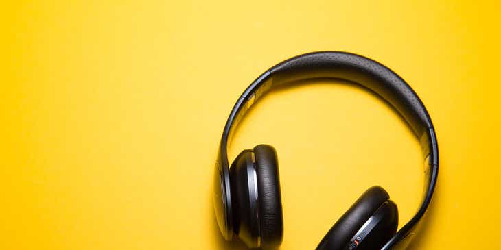 Auriculares de audio inalámbricos en una superficie amarilla en un logo para audio.