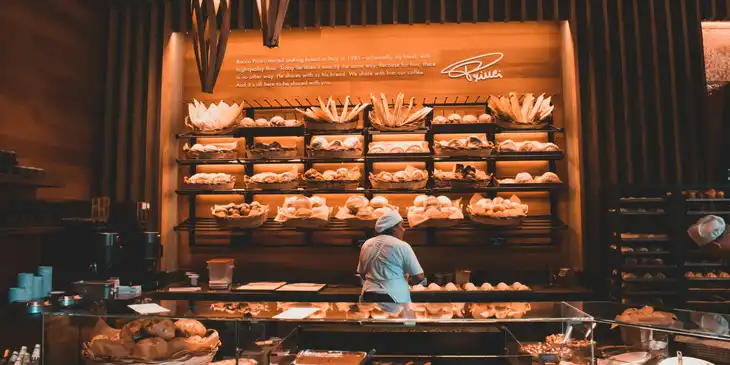 Eine Angestellte arbeitet hinter der Vitrine einer Bäckerei.