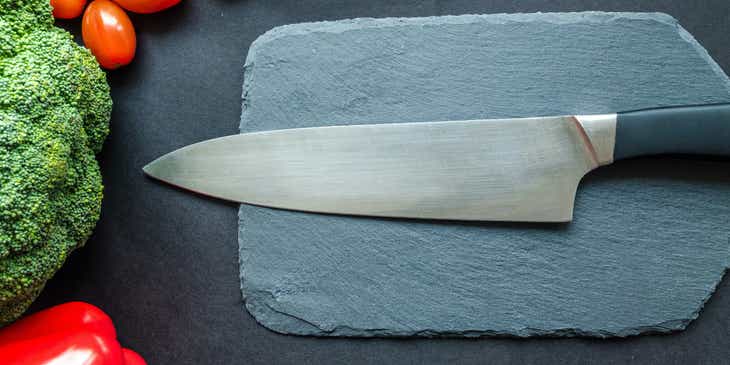 Sebzeleri doğramak üzere kesme tahtasının üstüne koyulan bir bıçak.
