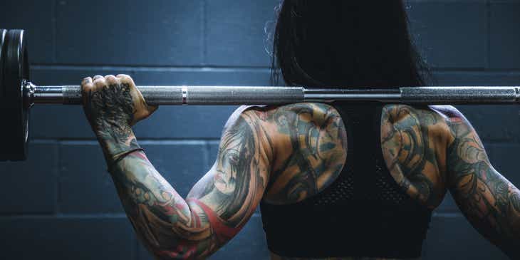 Seorang bodybuilder yang badass sedang mengangkat beban di gym.