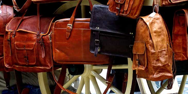 A cart filled with an assortment of leather bags.