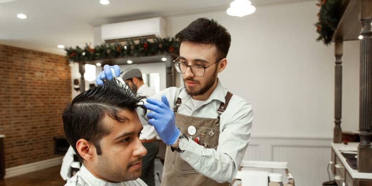 A barber working with a client in a barbershop.