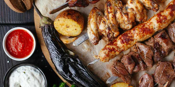 Un piatto da portata con carne e verdure grigliate, il tutto accompagnato da un mix di salse barbecue.
