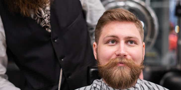 Saçını kestirdikten sonra sakalını yağlayan bir adam.