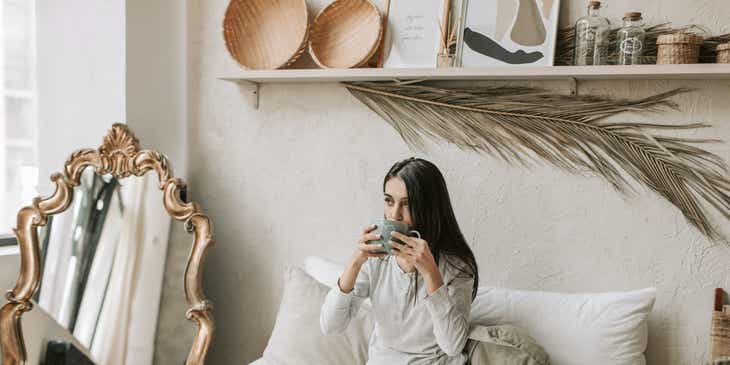 Seorang wanita menikmati kopi dan croissant di kamarnya di sebuah bed and breakfast.