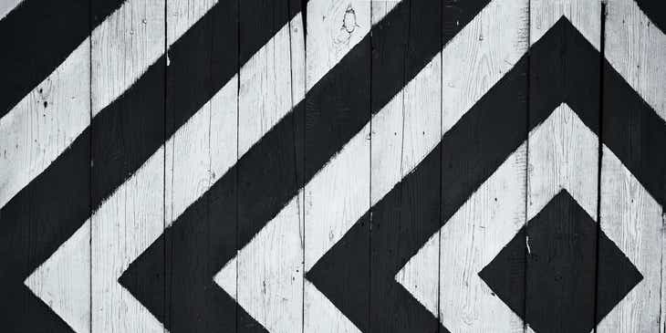 Ein Muster mit schwarz-weißen Rechtecken auf einer Holzwand.