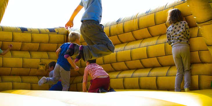 Un grupo de niños jugando en un castillo inflable, en un logo para inflables.