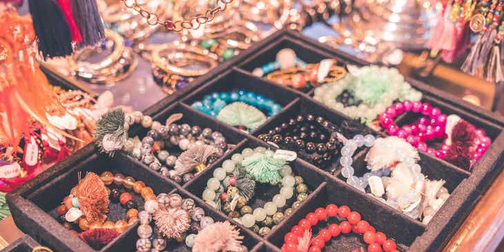 Des plateaux d'échantillons de bracelets de perles dans un magasin.