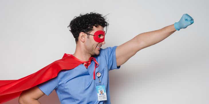 Un medico con maschera e mantello nella classica posa da supereroe.