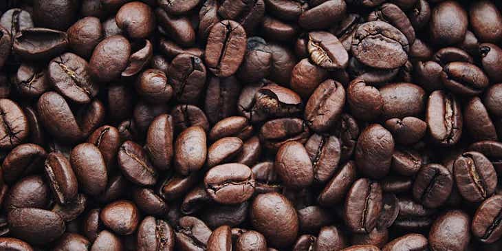 Dunkelbraune Kaffeebohnen liegen nach dem Rösten eng beisammen.