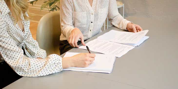 Masa başında beyaz bir kağıda iş teklifi yazan bir kadın.
